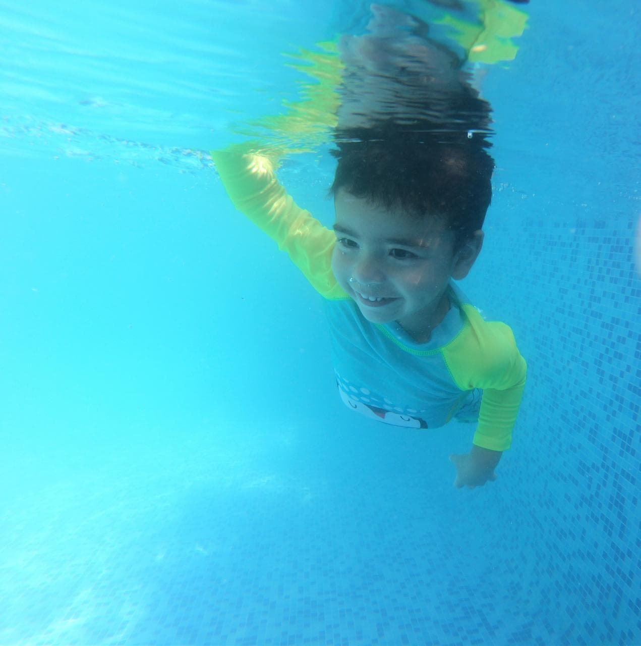 Un niño sonriendo mientras nada en una piscina